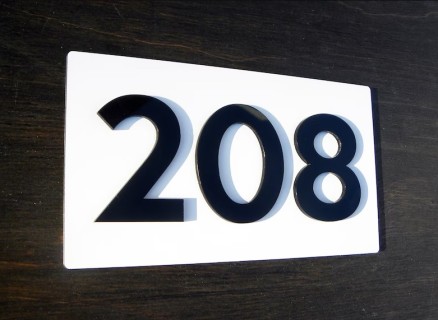 Mat wit huisnummerbord met zwarte cijfers